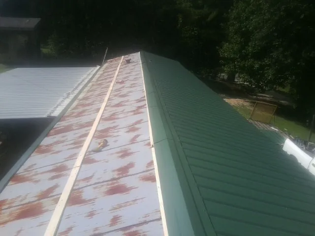 Old rusted panels beside newly installed green metal roofing — Wind Damage Roof Repair by Roofing Brothers in Lookout Mountain